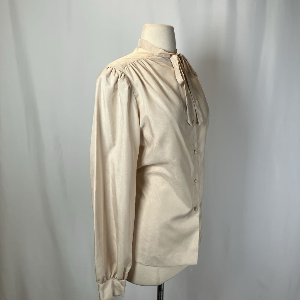 Beige blouse on a mannequin against a plain background