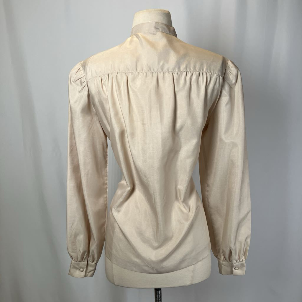Beige blouse on a mannequin against a plain background