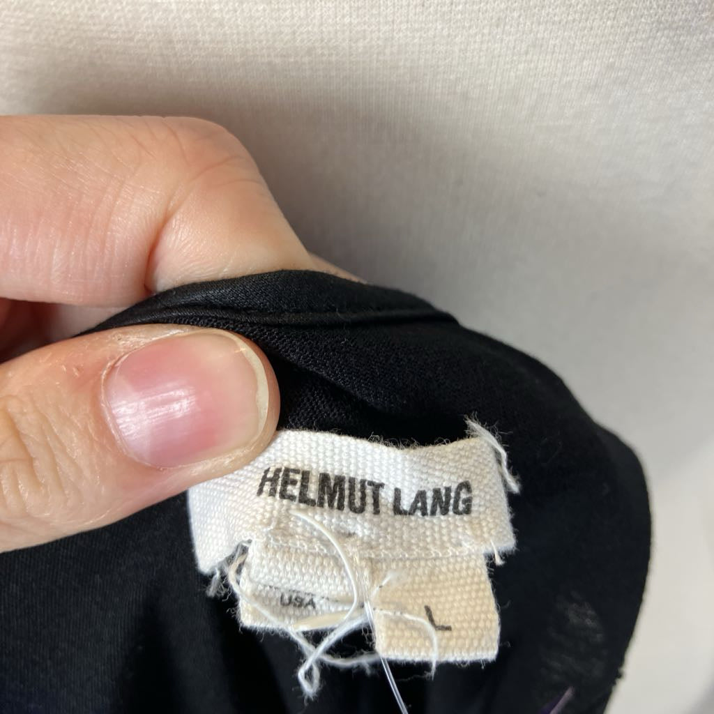 Hand holding a black garment with a Helmut Lang label.
