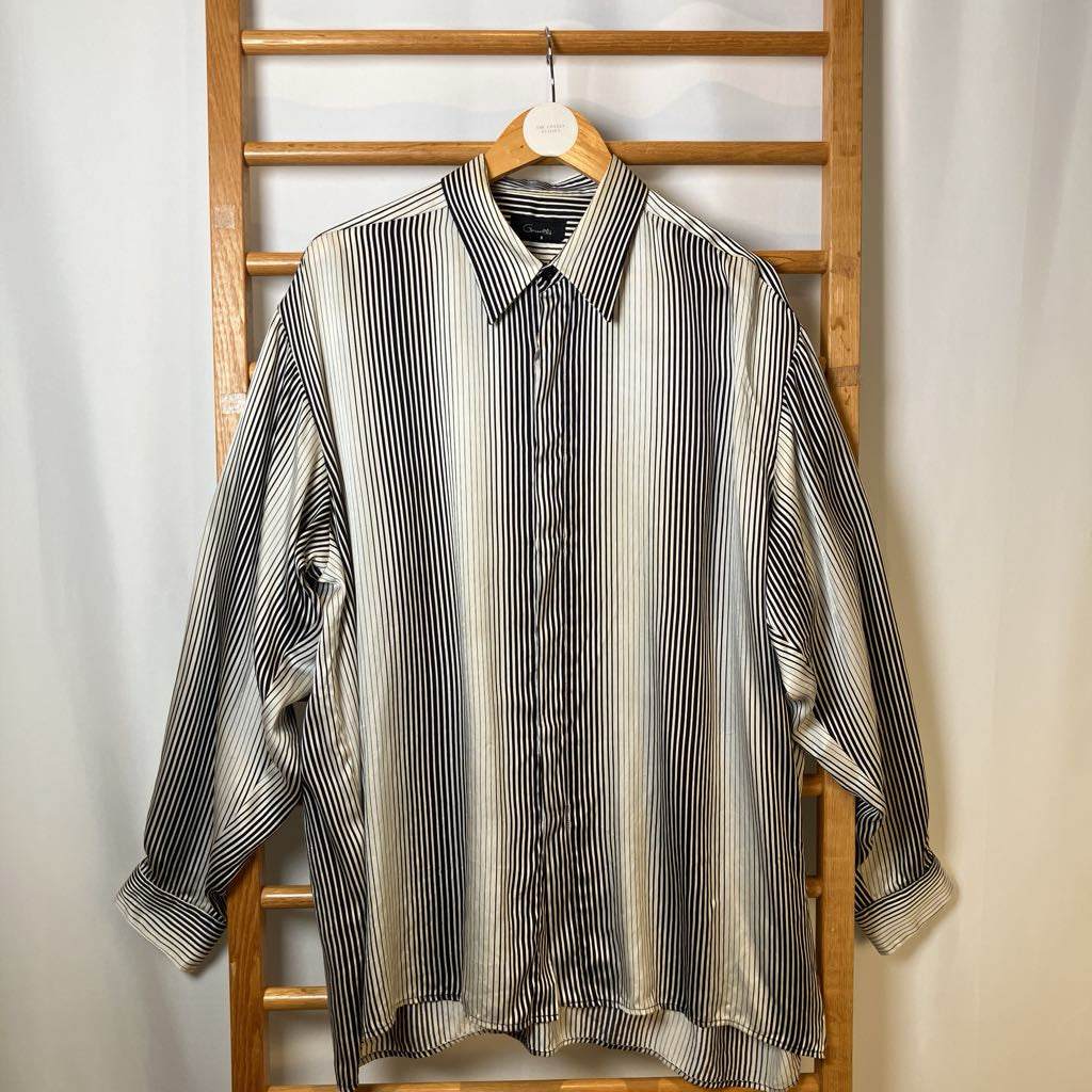Striped shirt hanging on a wooden rack against a white wall