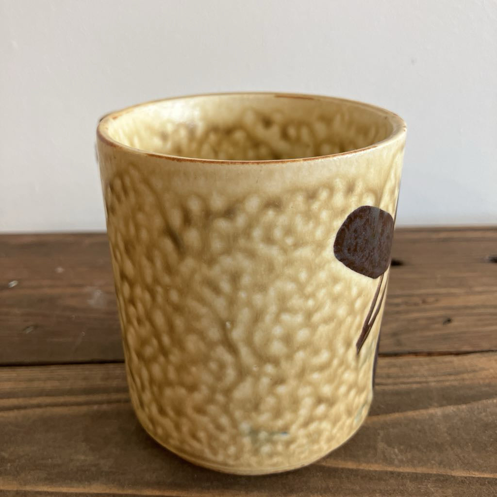 Textured ceramic cup on a wooden surface with a neutral background