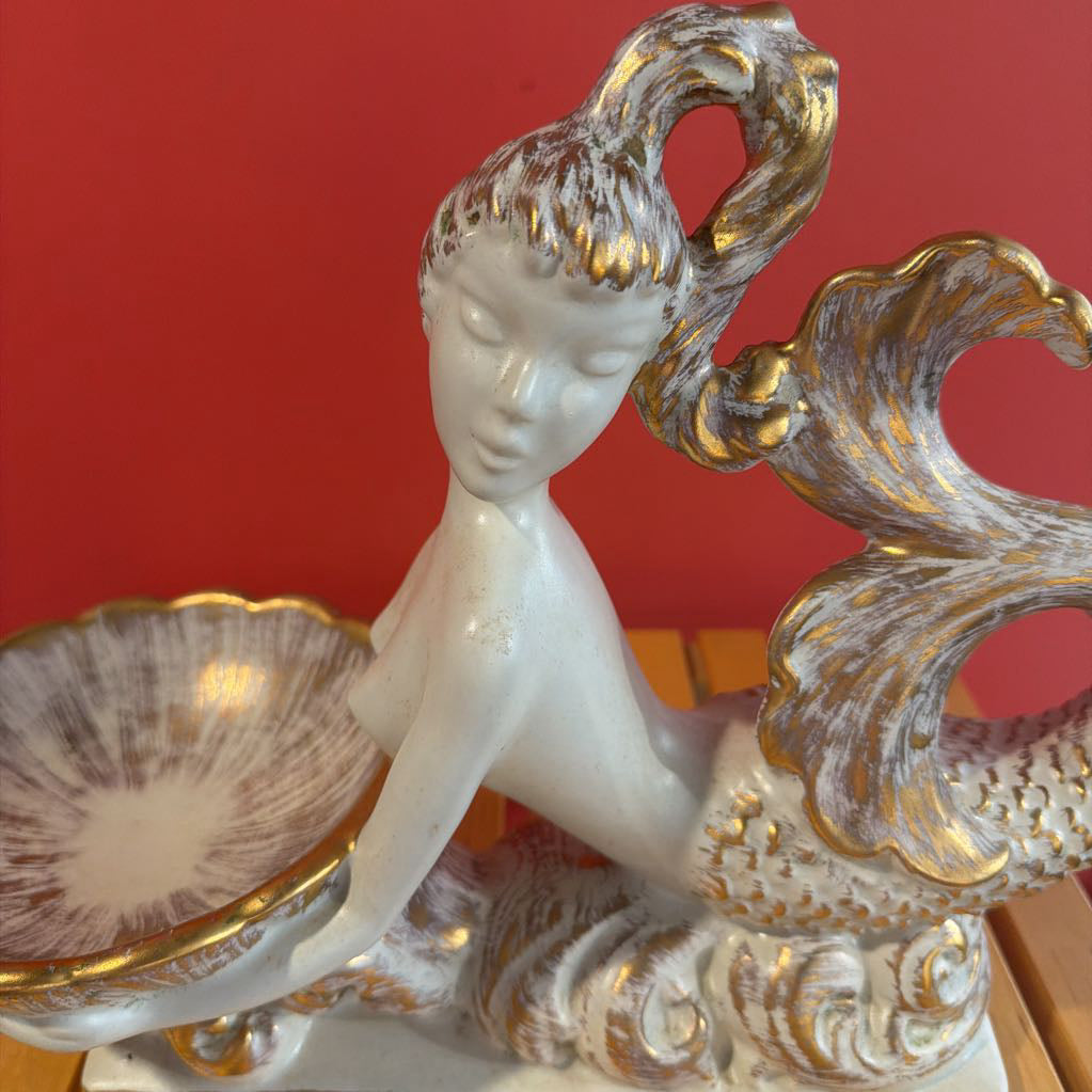 Decorative sculpture of a woman with gold accents against a red background