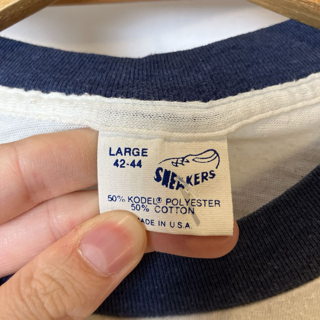 Close-up of a clothing tag on a striped shirt with 'Sneakers' branding.