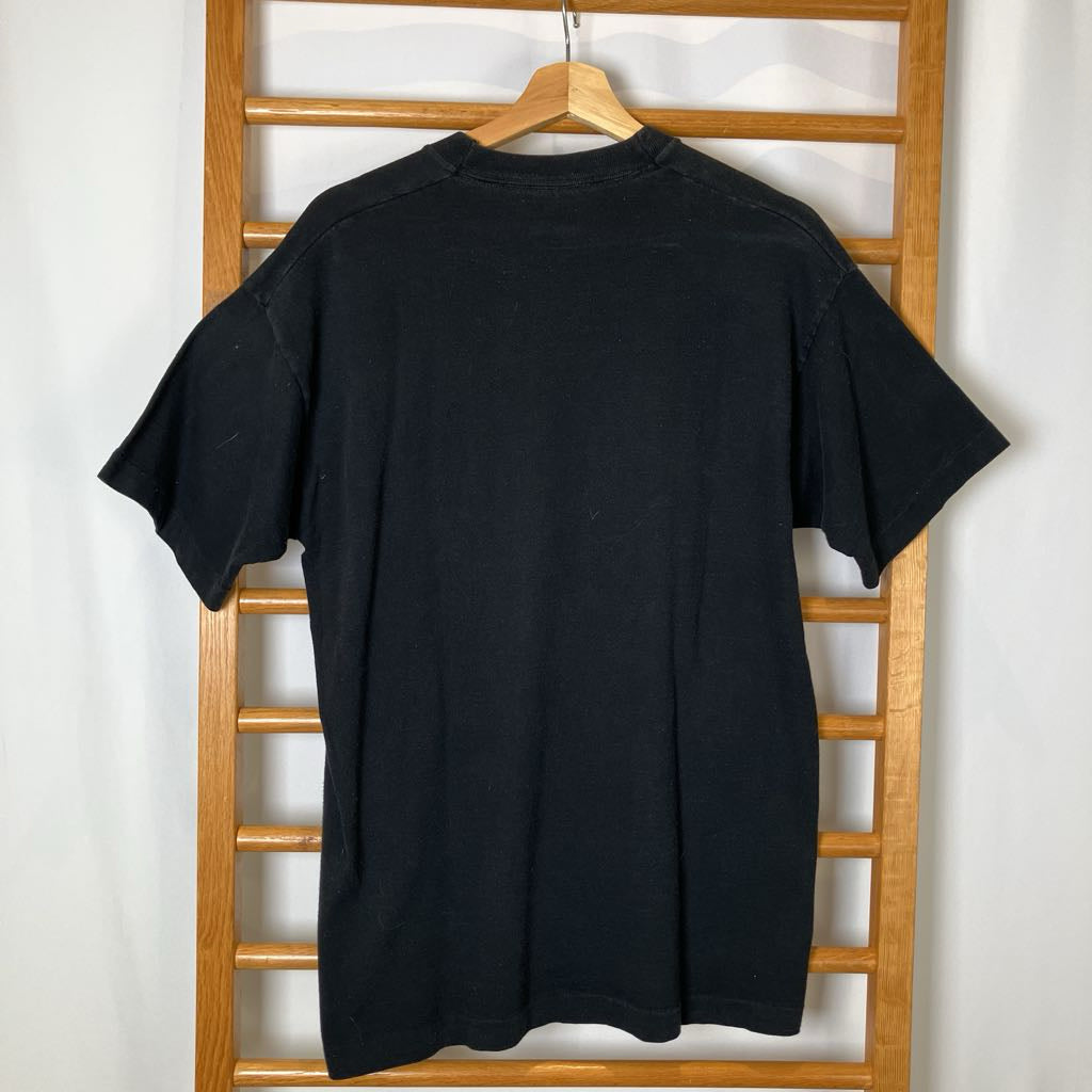 Black t-shirt on a wooden hanger against a white wall