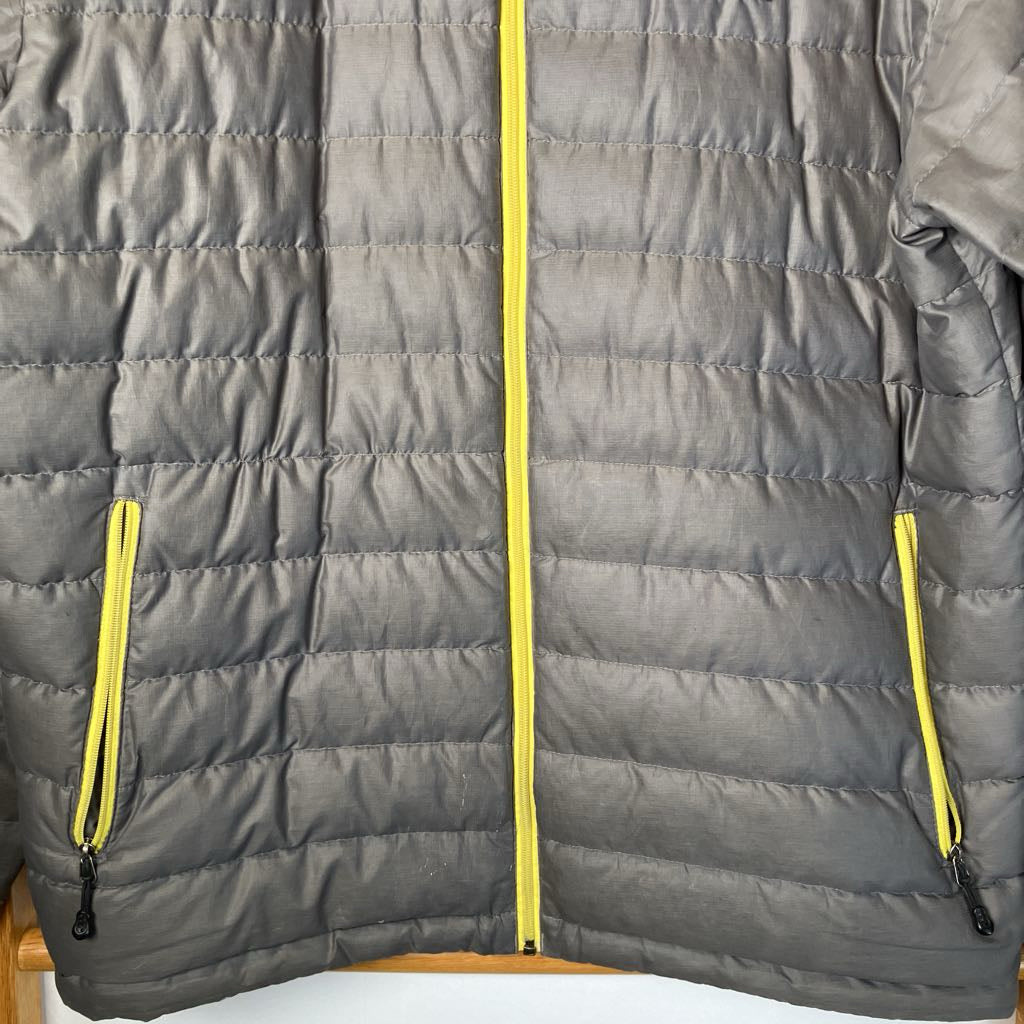 Gray puffer jacket with yellow zippers on a white background