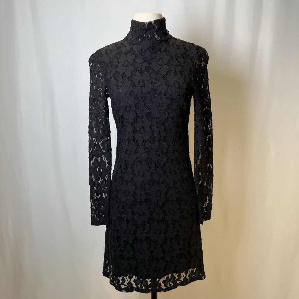 Black lace dress on a mannequin against a plain background