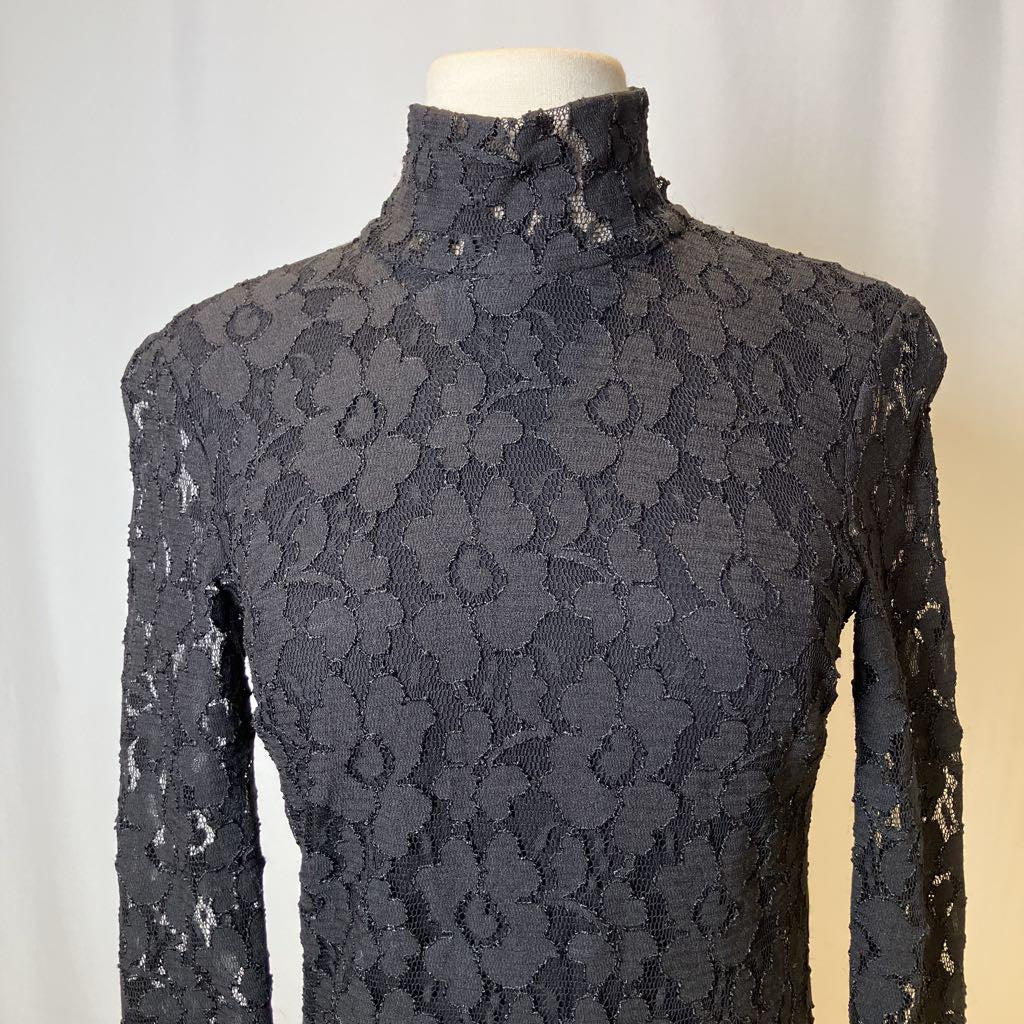 Black lace top on a mannequin against a neutral background