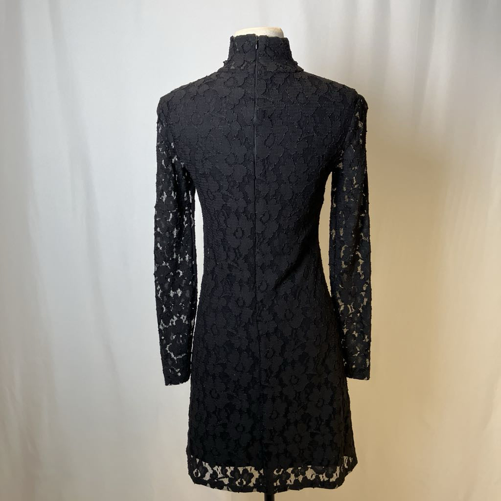 Black lace dress on a mannequin against a plain background