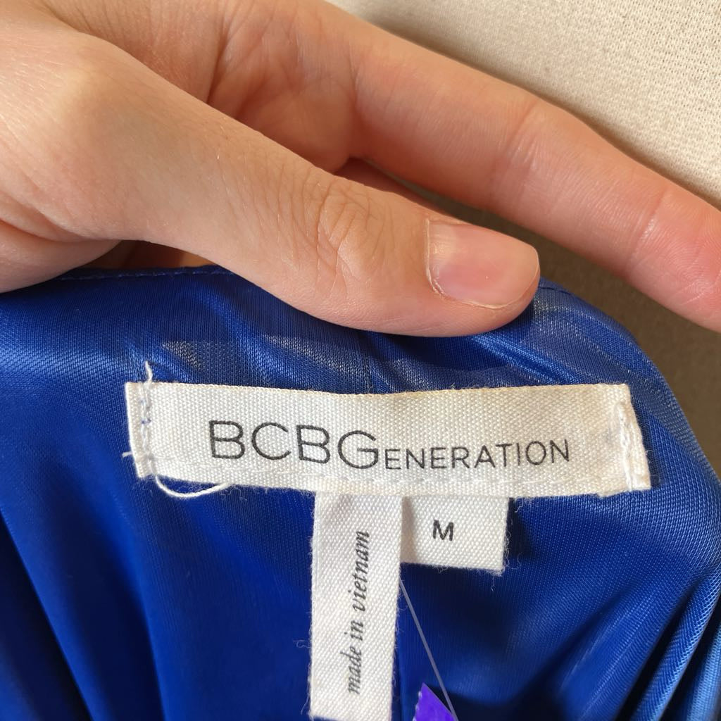 Hand holding a blue garment with a BCBGeneration label.