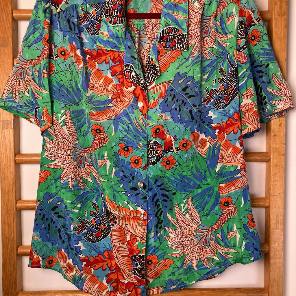 Colorful floral-patterned shirt hanging on a wooden rack.