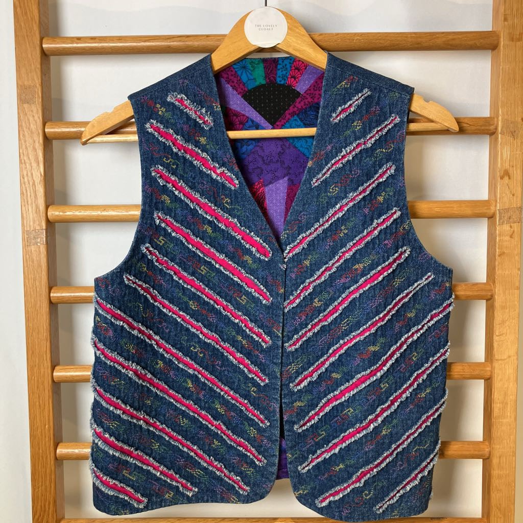 Blue patterned vest on a wooden hanger against a white wall