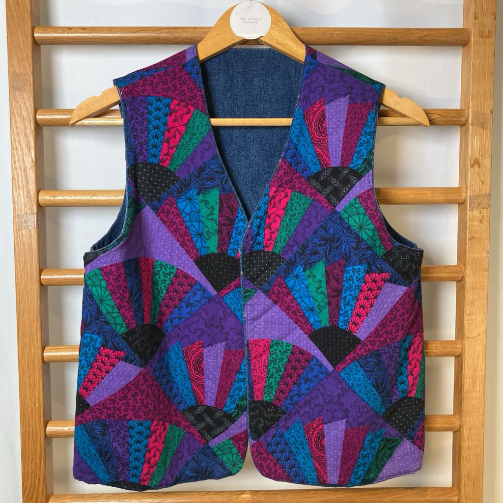 Colorful quilted vest on a wooden hanger against a wooden ladder background