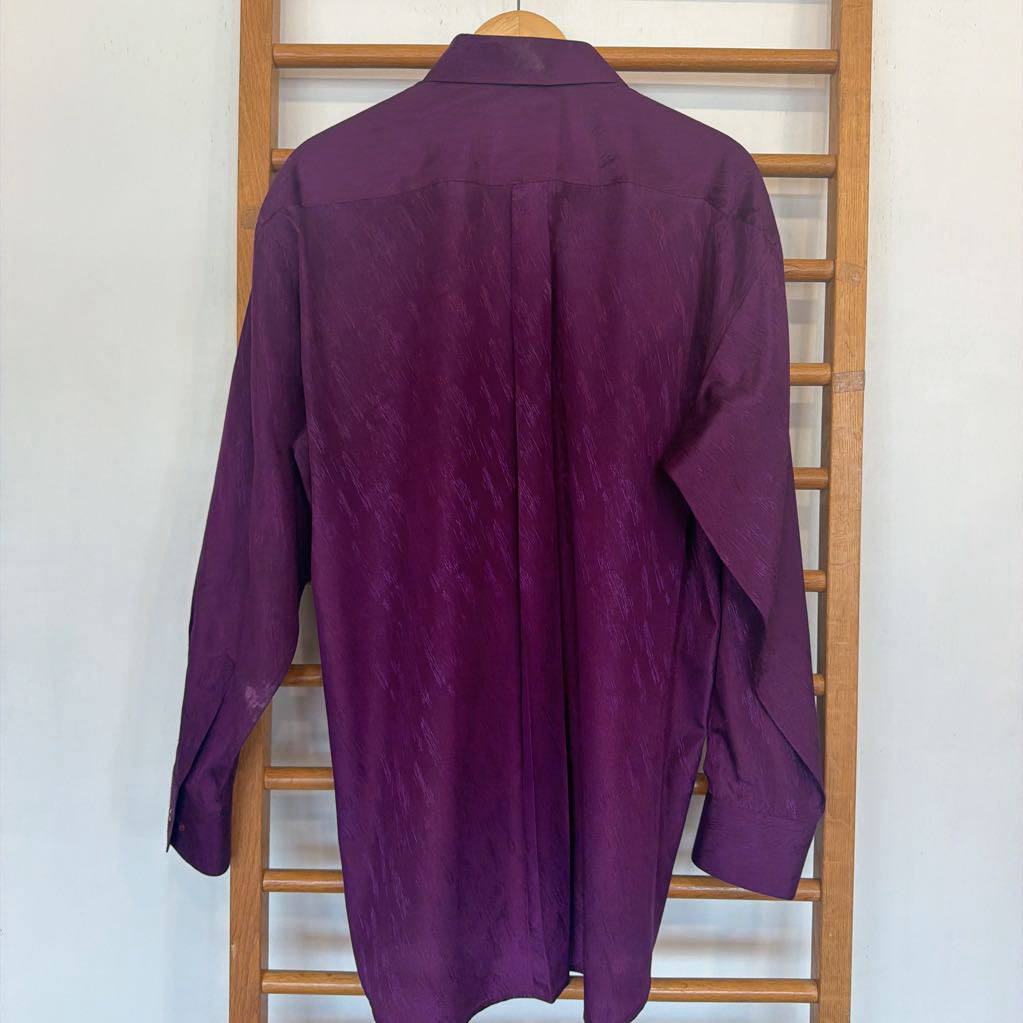 Purple shirt on a wooden hanger against a white wall