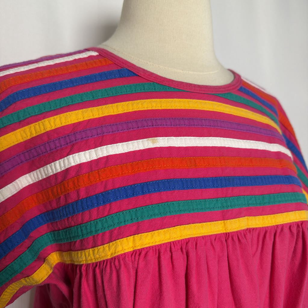 Pink ruffled maxi dress with striped design on a mannequin in front of a white wall.
