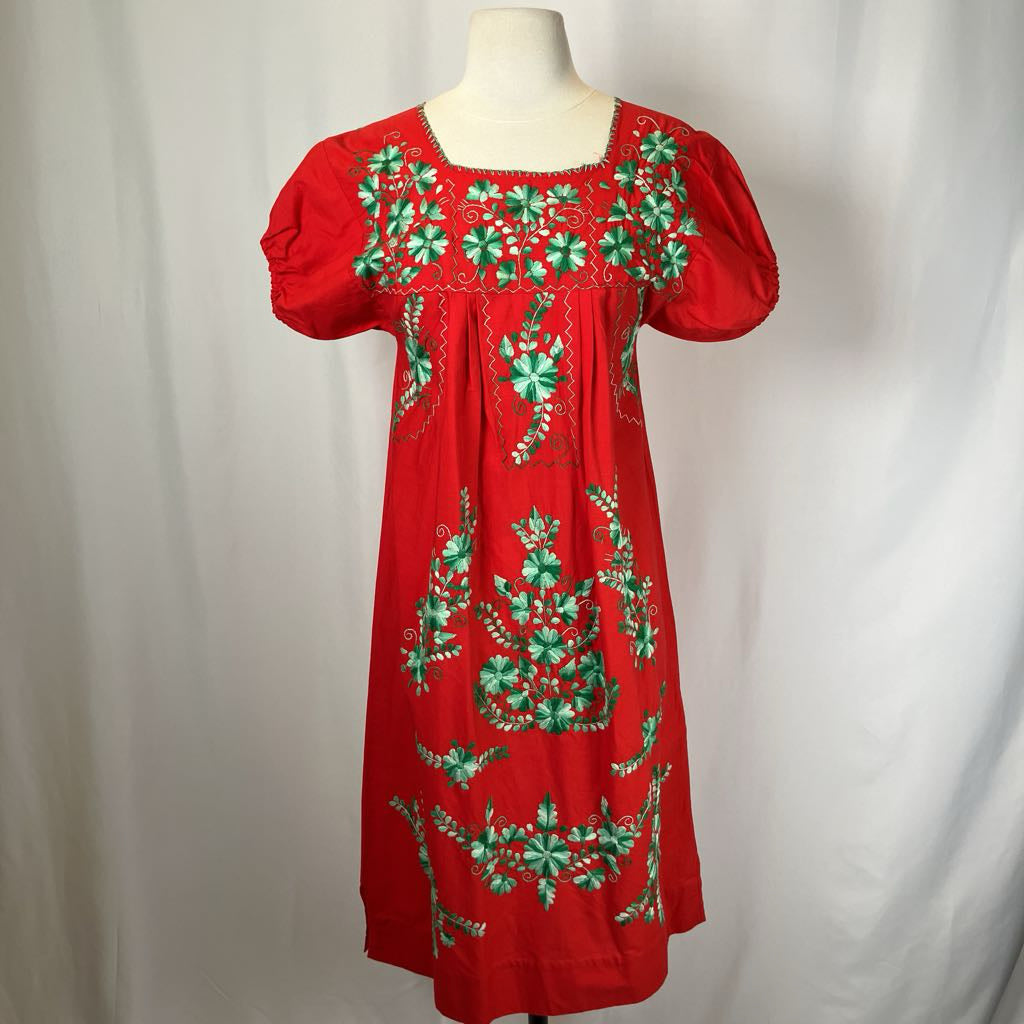 Red dress with green floral embroidery on a mannequin against a white background