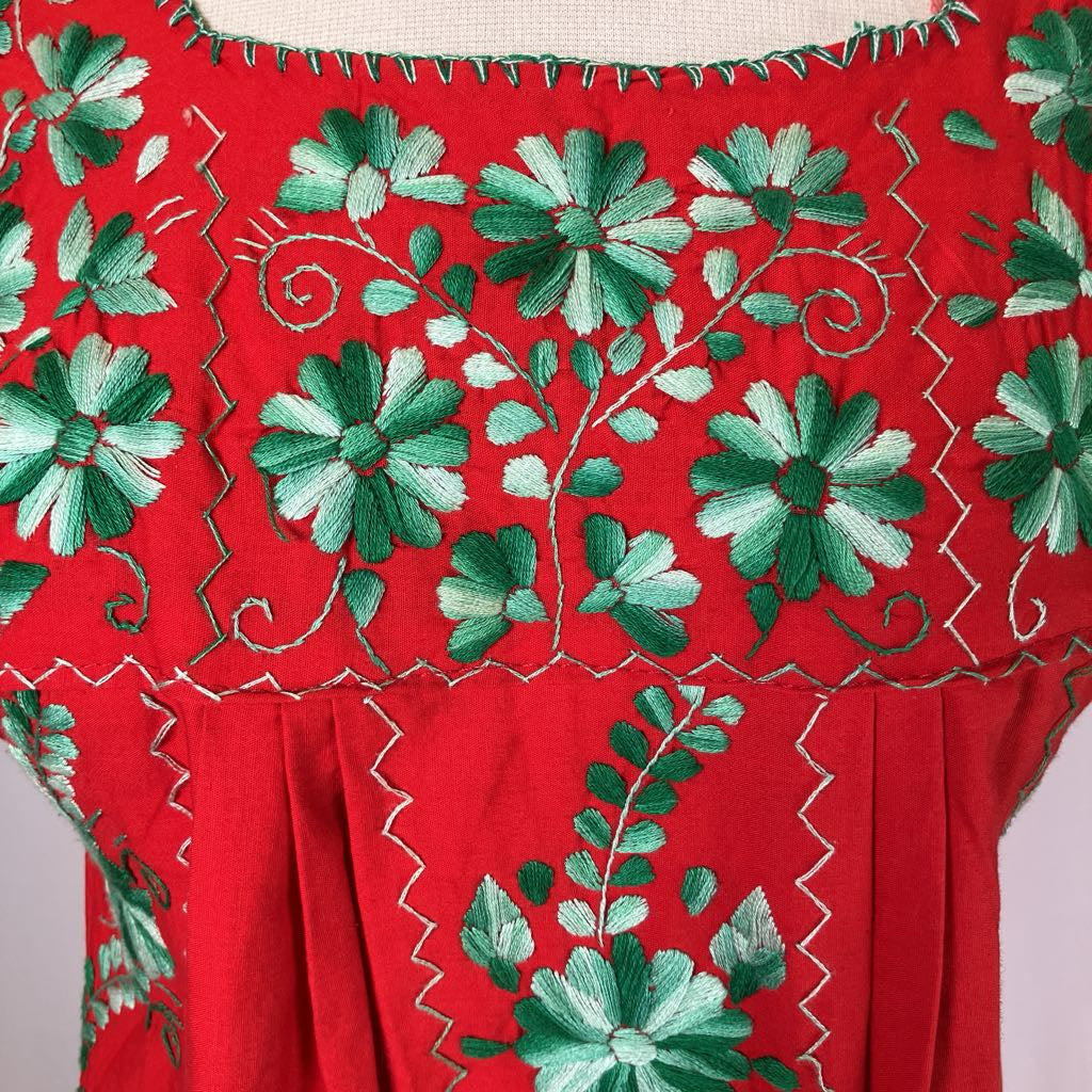 Red fabric with green floral embroidery on a beige background