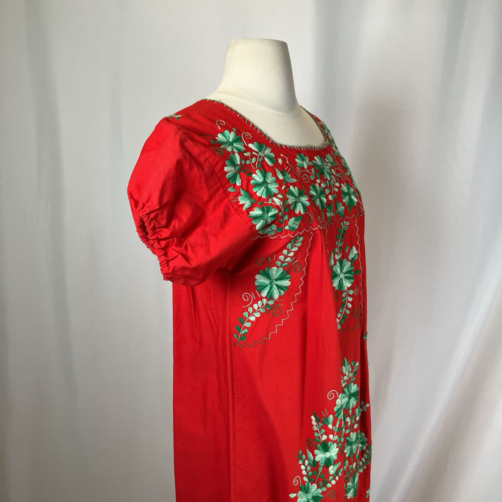 Red dress with green floral embroidery on a mannequin against a white background