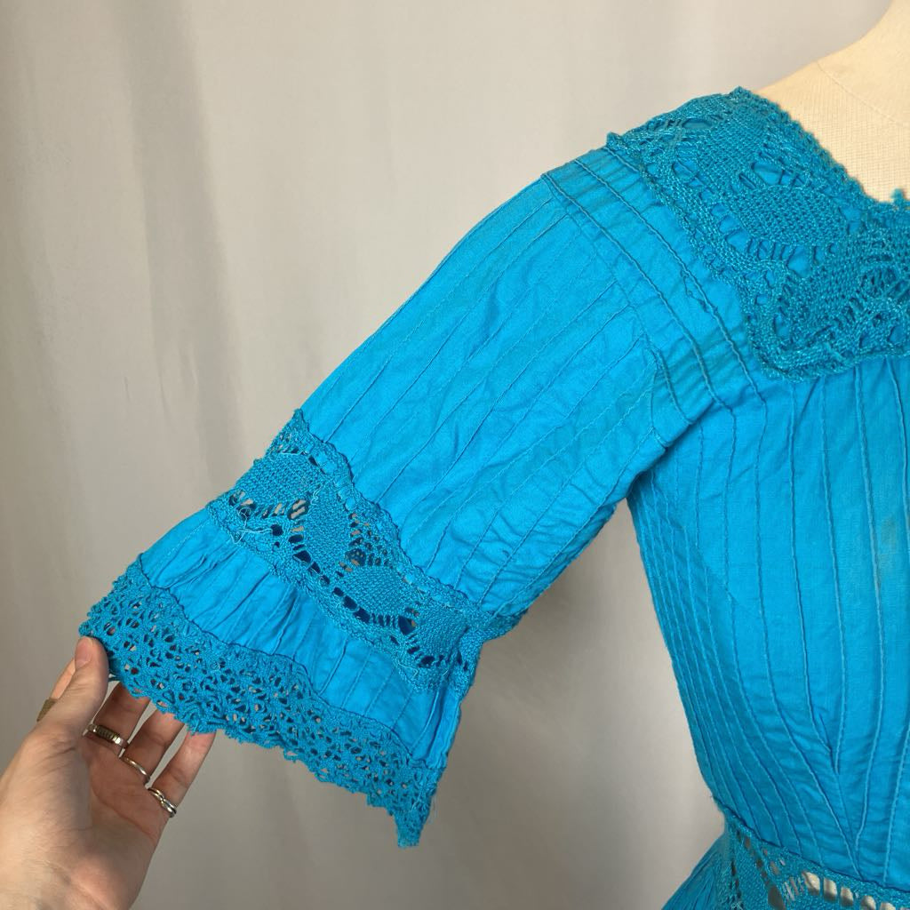 Close-up of a blue dress with lace details on a neutral background