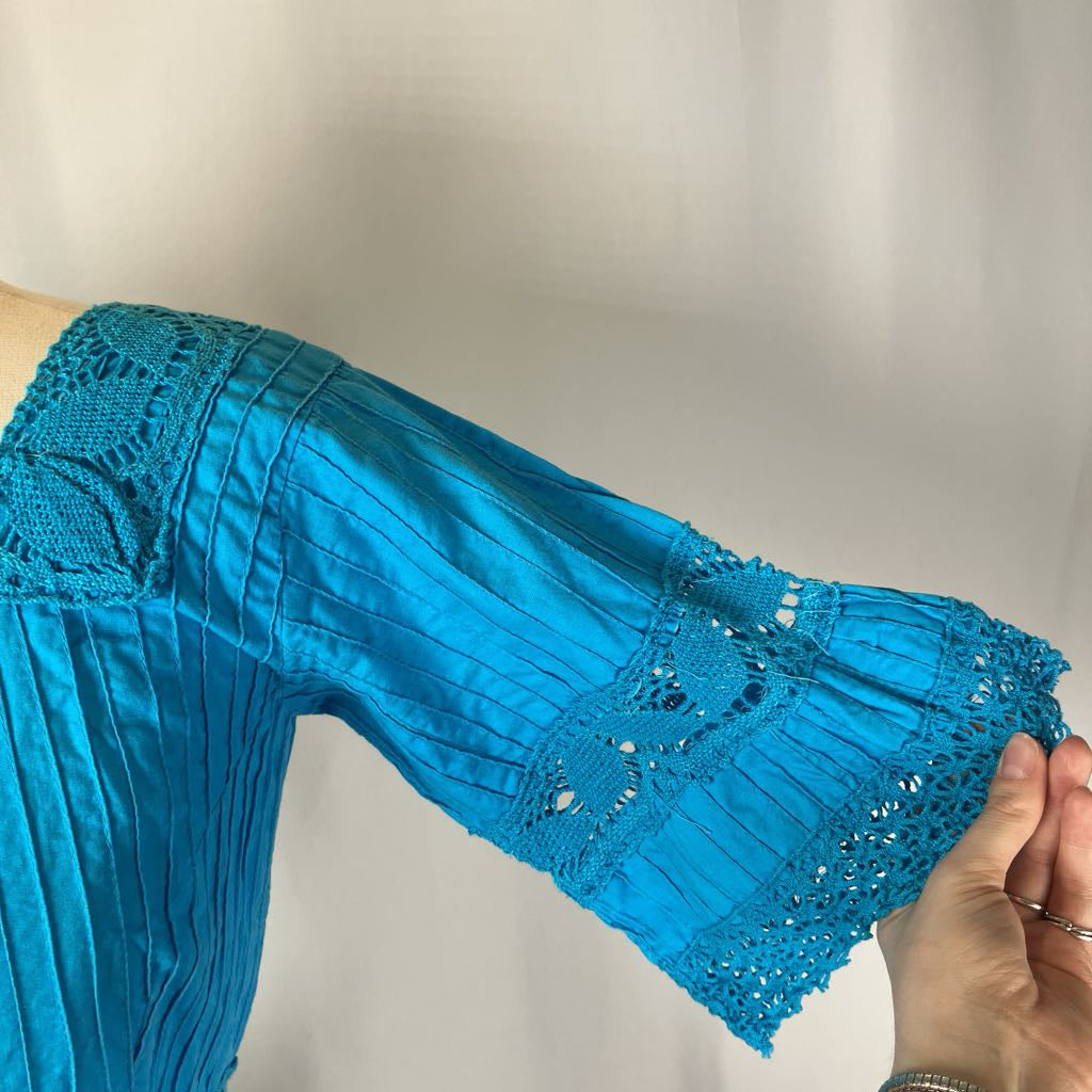 Close-up of a blue dress with intricate lace detailing on a plain background