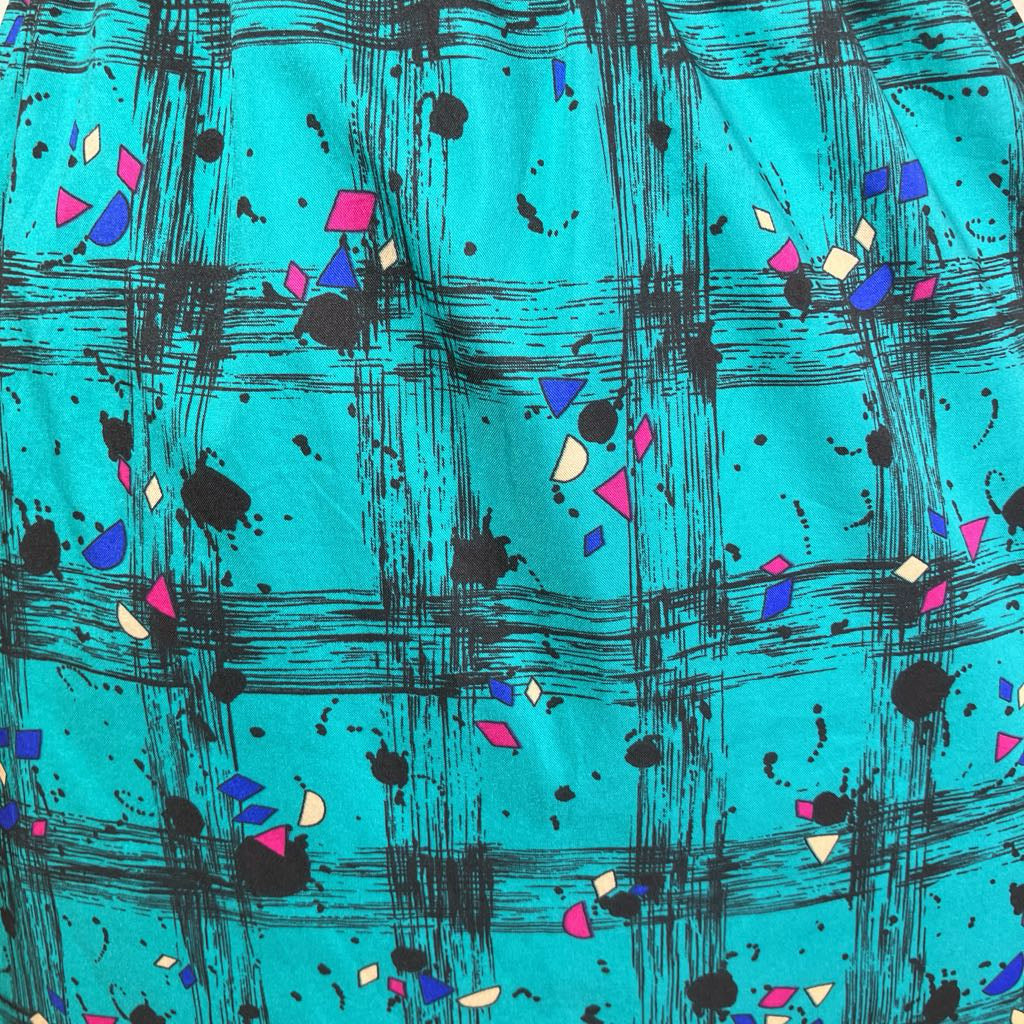 Turquoise fabric with black abstract patterns and colorful geometric shapes