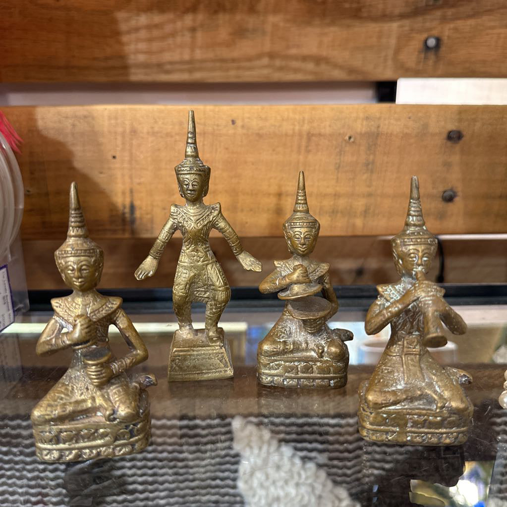 Set of four gold-colored figurines on a reflective surface with a wooden background