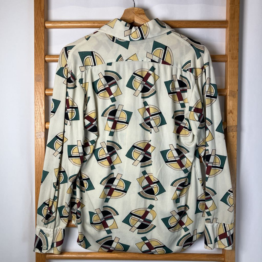 Shirt with geometric pattern hanging on a wooden rack against a white wall