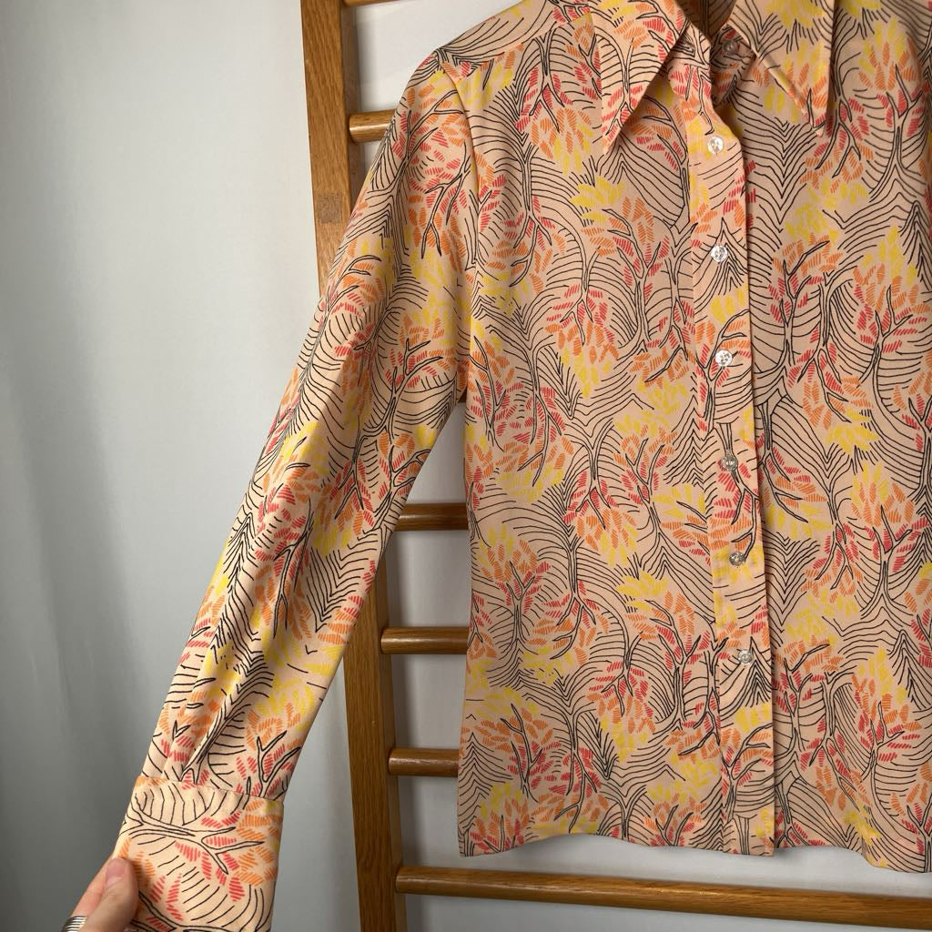 Floral patterned shirt on a wooden hanger against a gray wall