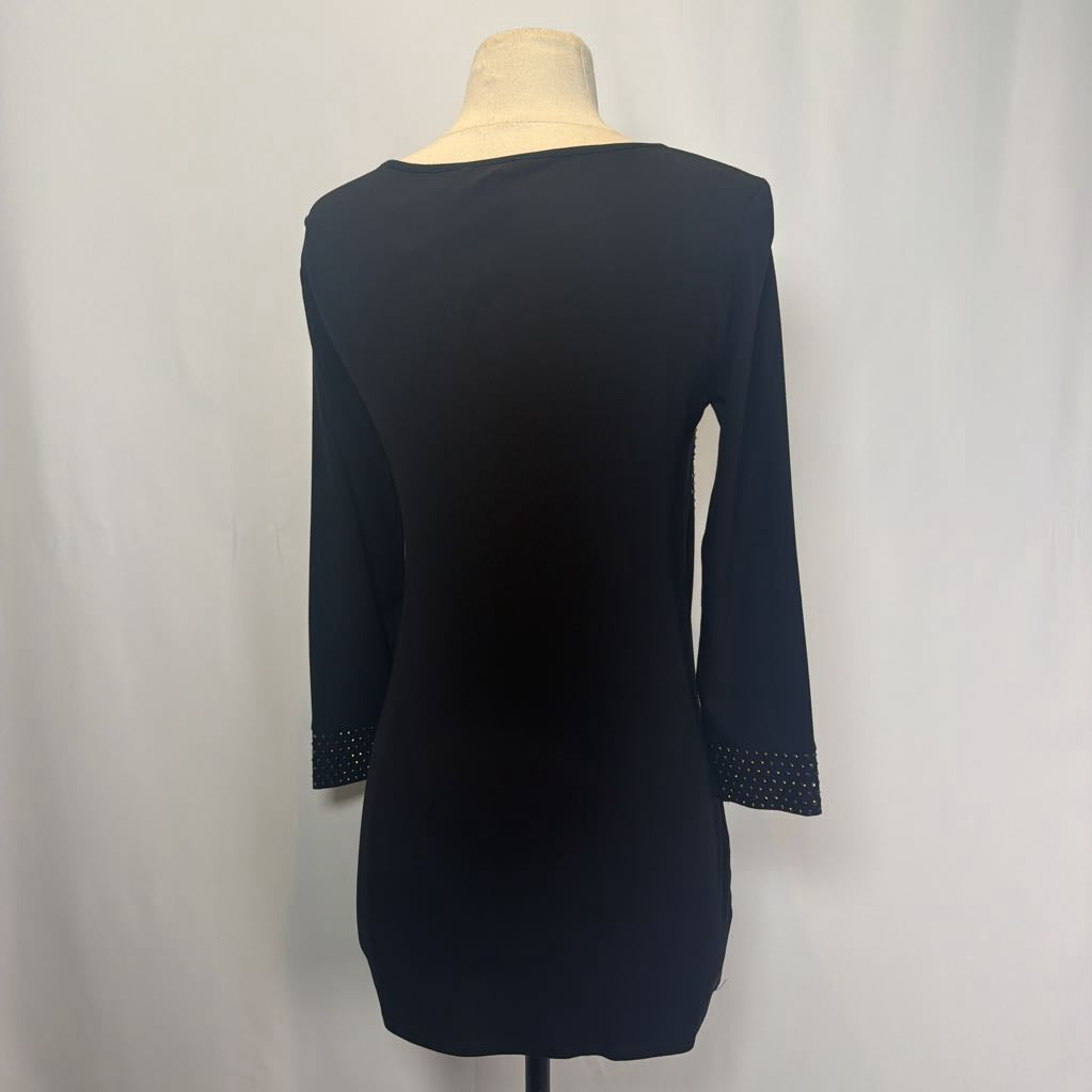 Black dress on a mannequin in front of a white wall.