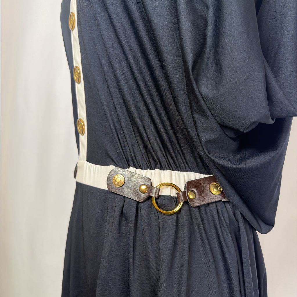 black dress with gold button details against white backdrop