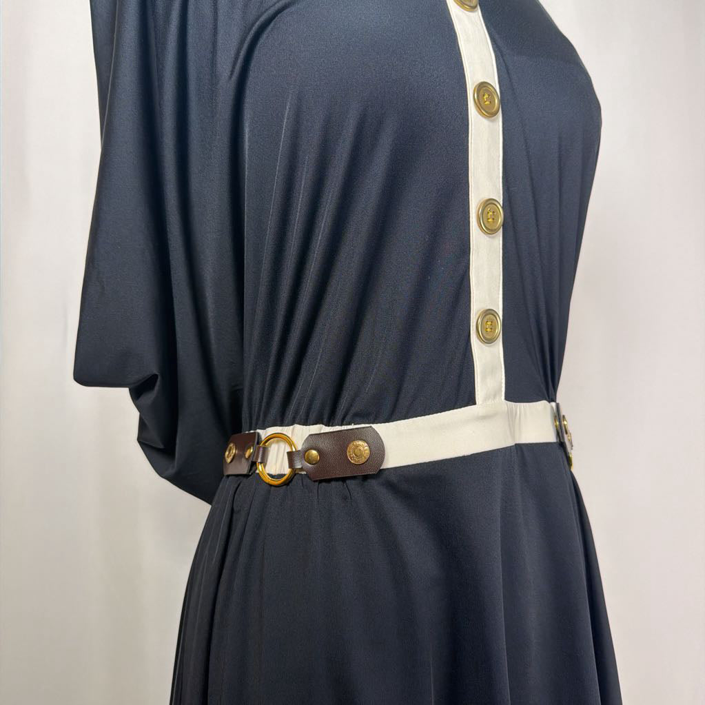 black dress with gold button details against white backdrop