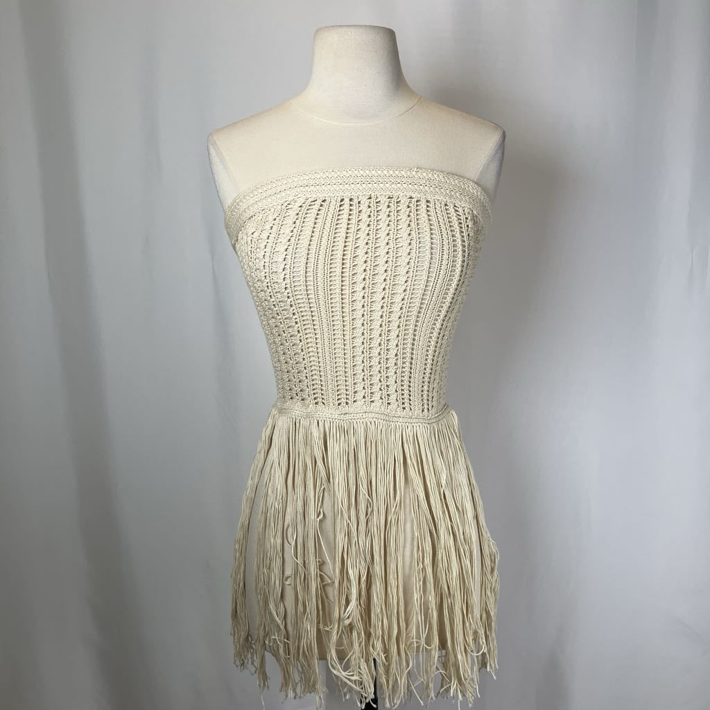Beige crochet dress with fringe on a mannequin against a plain background