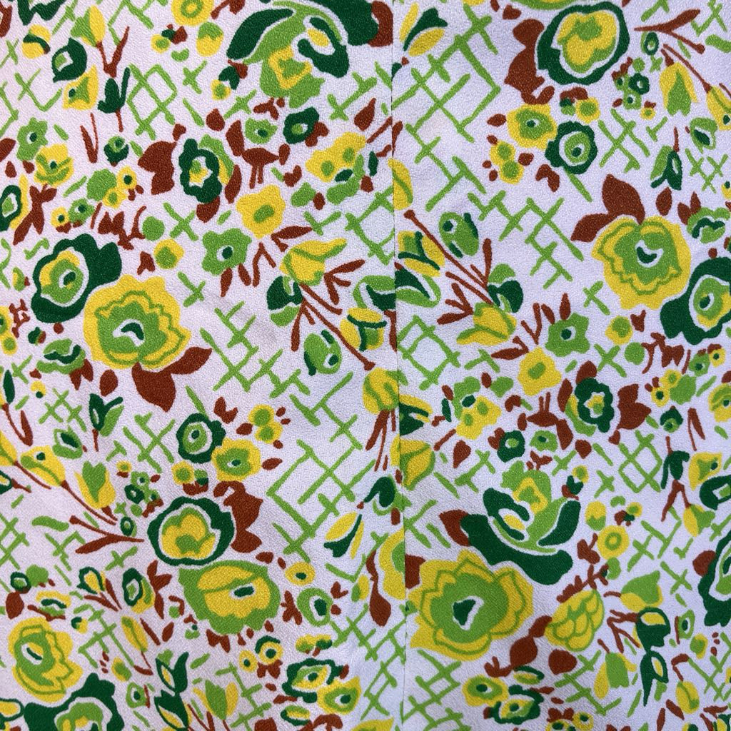 Patterned fabric with green, yellow, and brown flowers on a white background