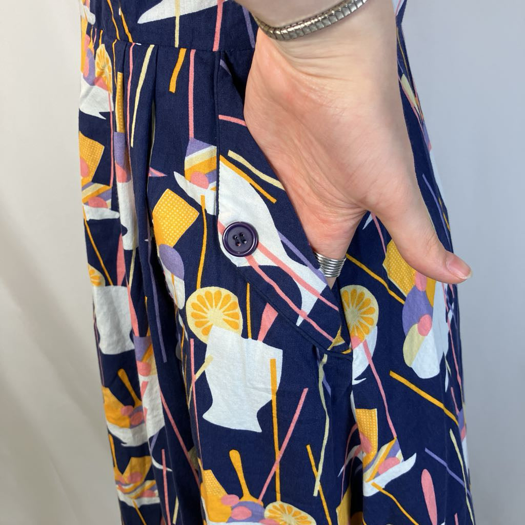 Navy blue dress with colorful abstract pattern, hand pointing to a pocket.