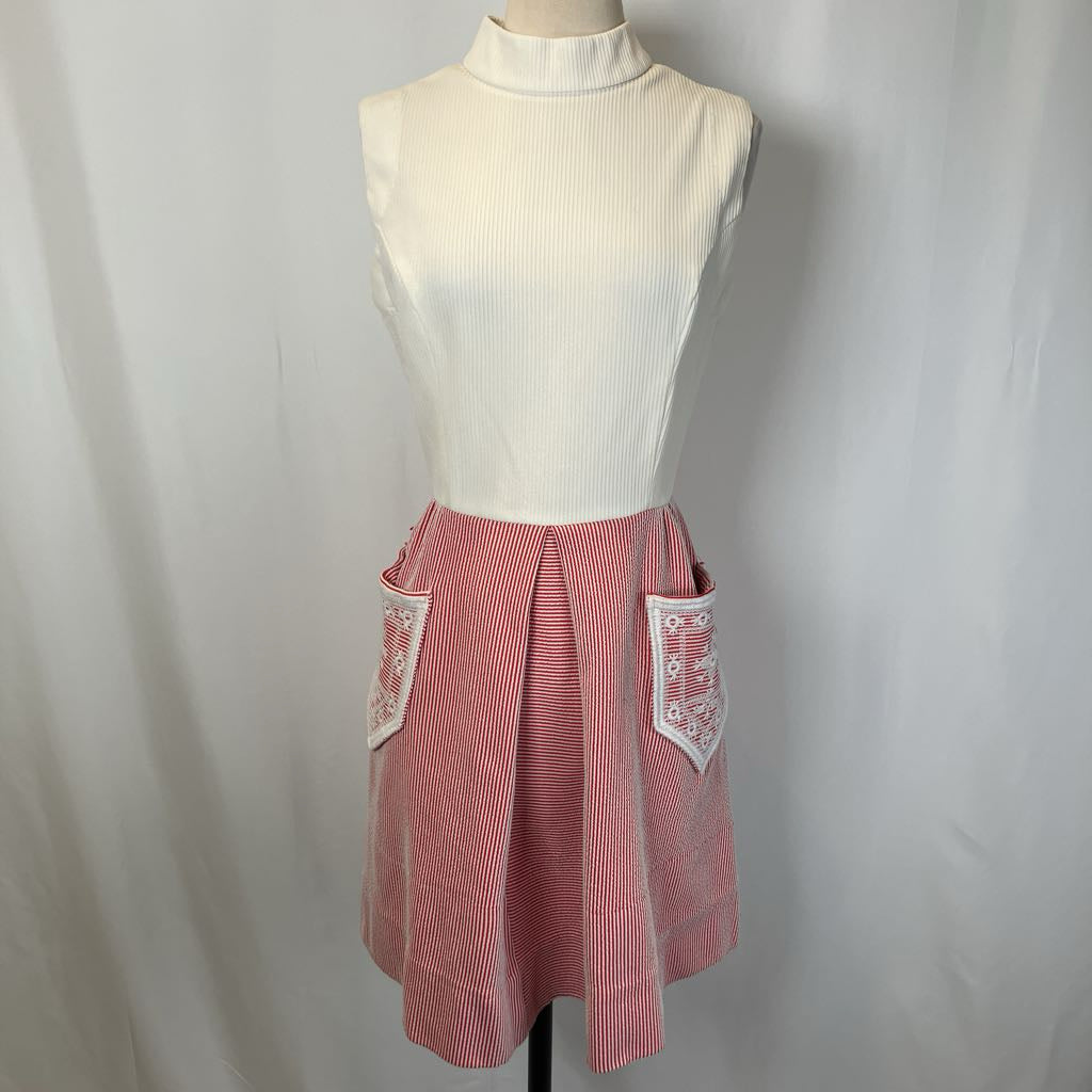 Mannequin wearing a white sleeveless top and pink checkered skirt with decorative pockets on a plain background
