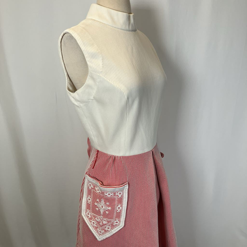 Mannequin wearing a white sleeveless top and red skirt with embroidery on a plain background