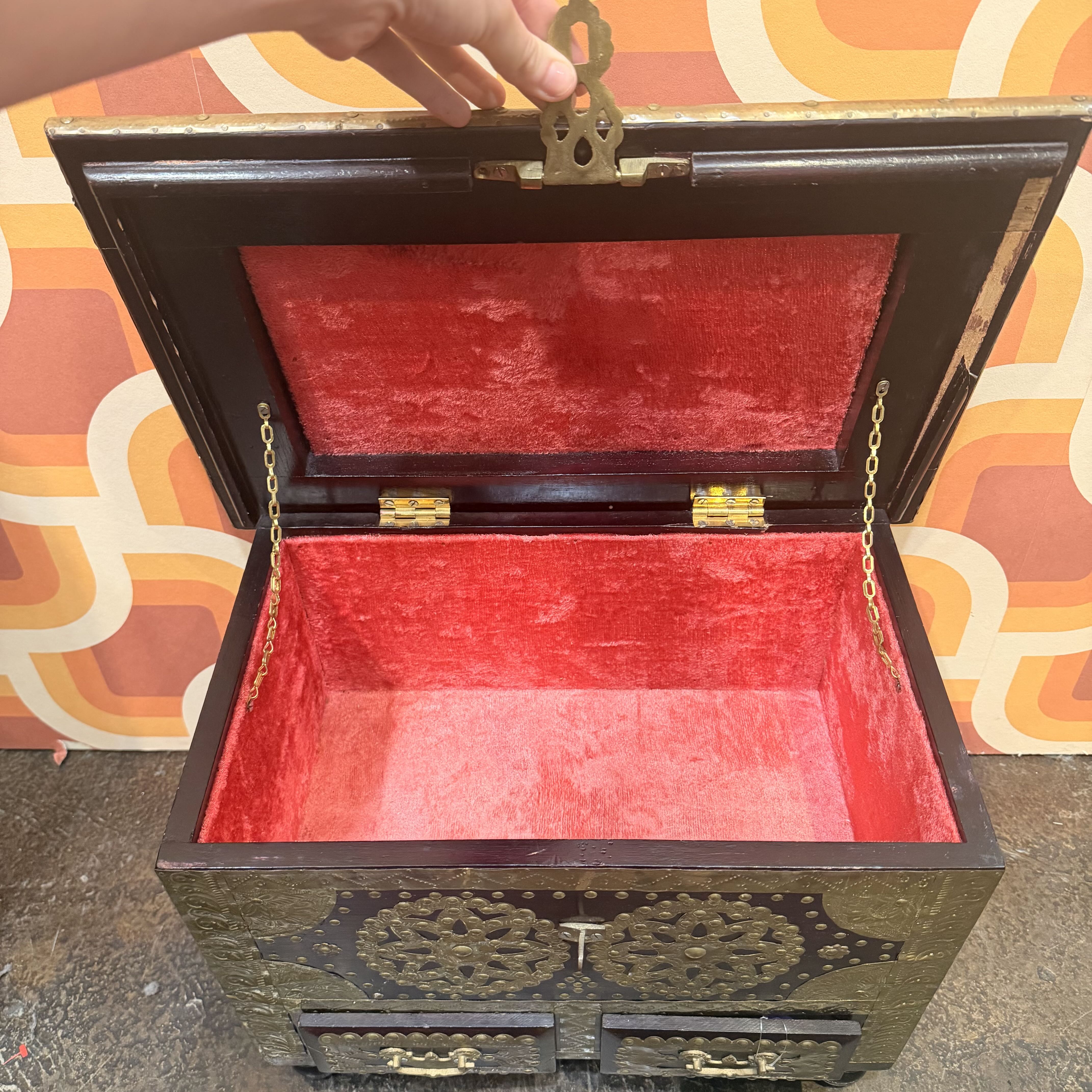 Decorative wooden box with red interior on a patterned surface