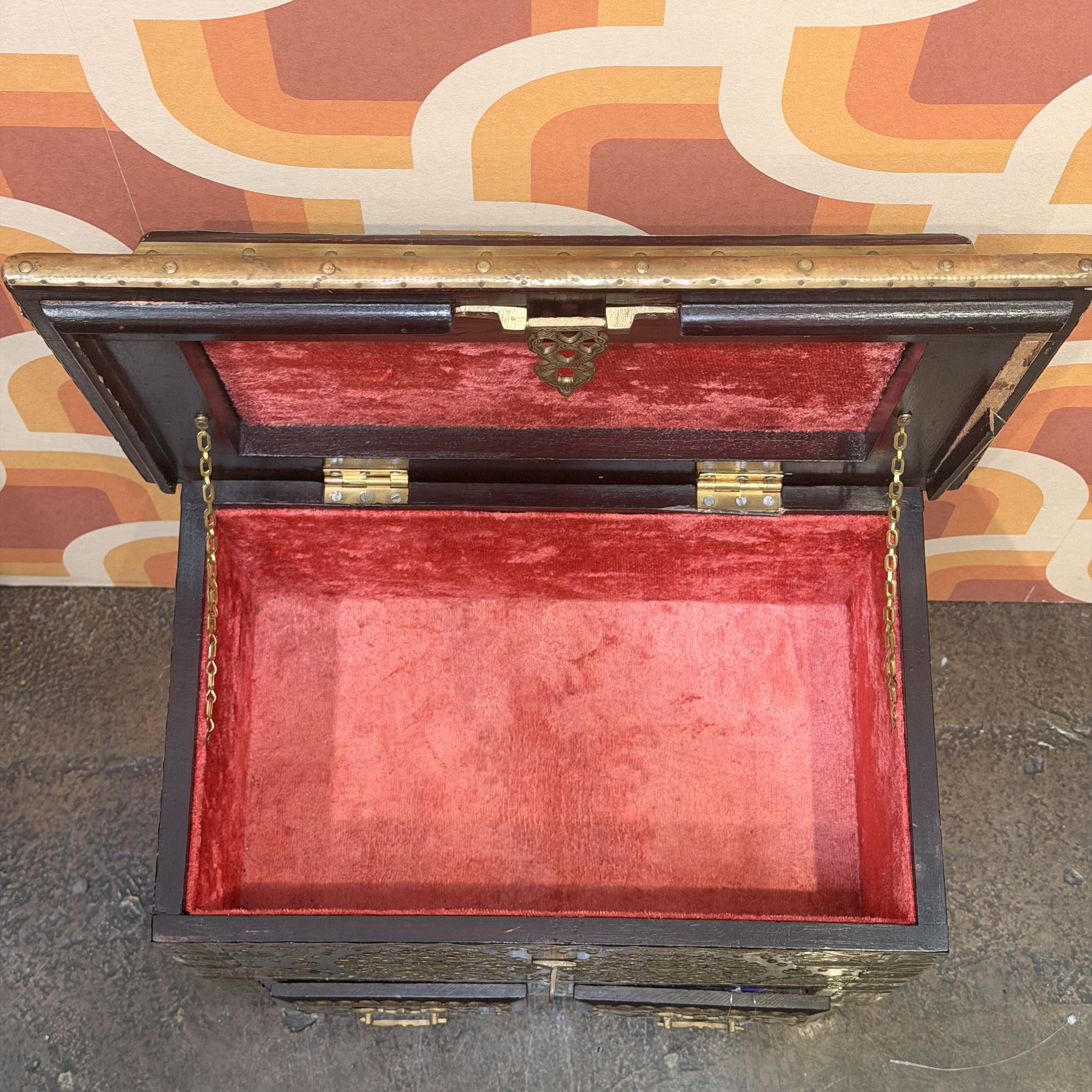 Open wooden box with red interior against a patterned wall.