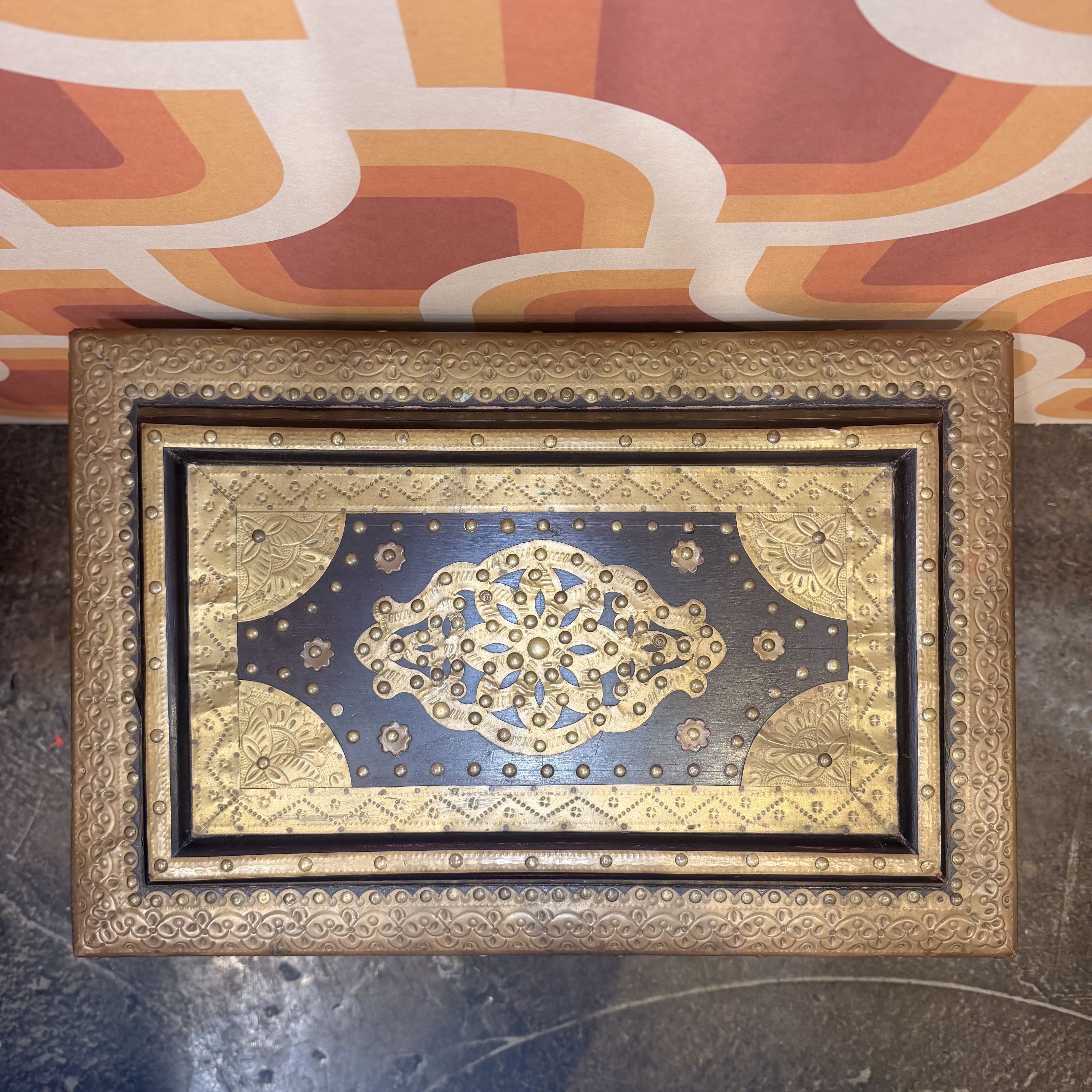 Decorative box with intricate gold and blue design on a textured surface with abstract patterned background