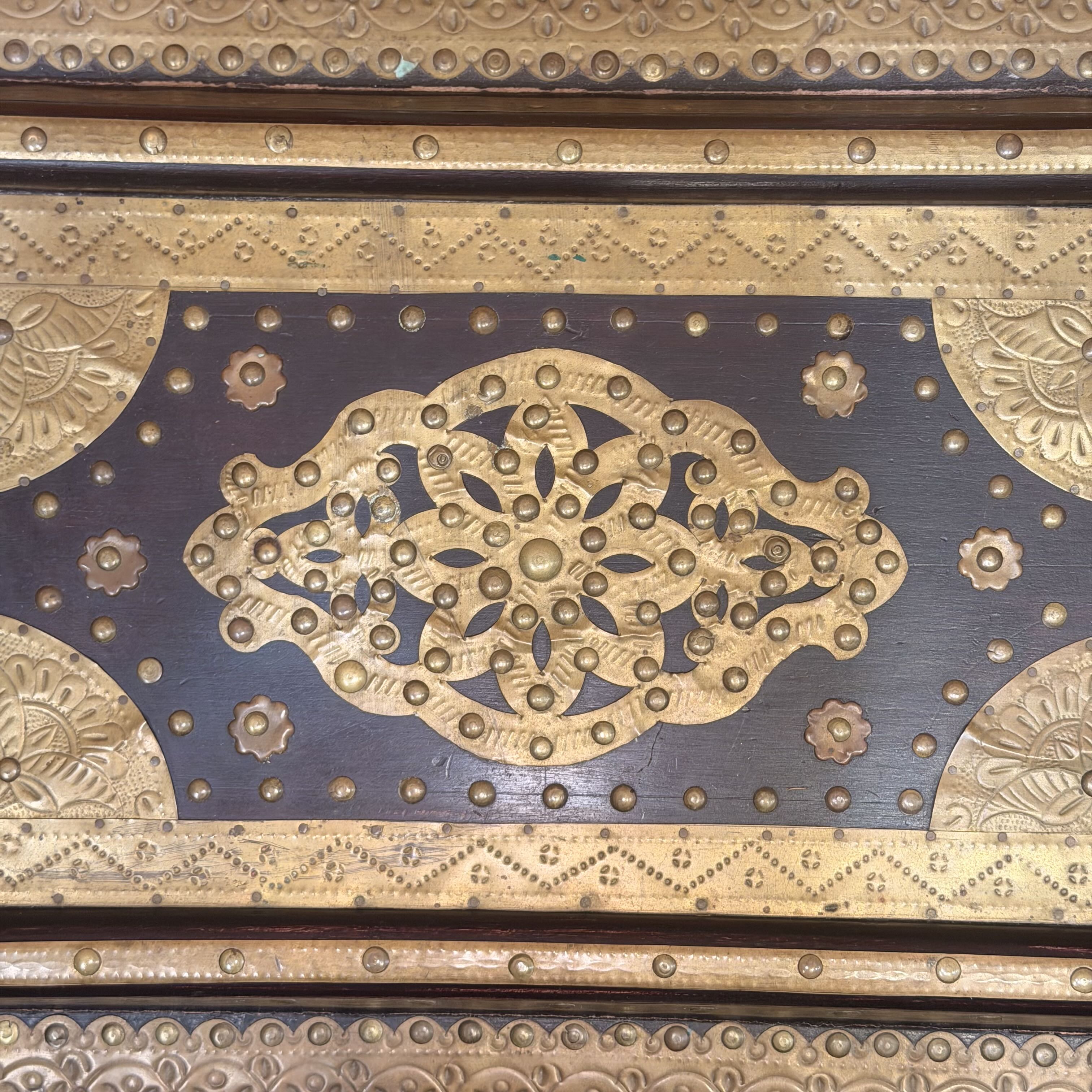 Decorative metalwork with intricate patterns on a wooden surface