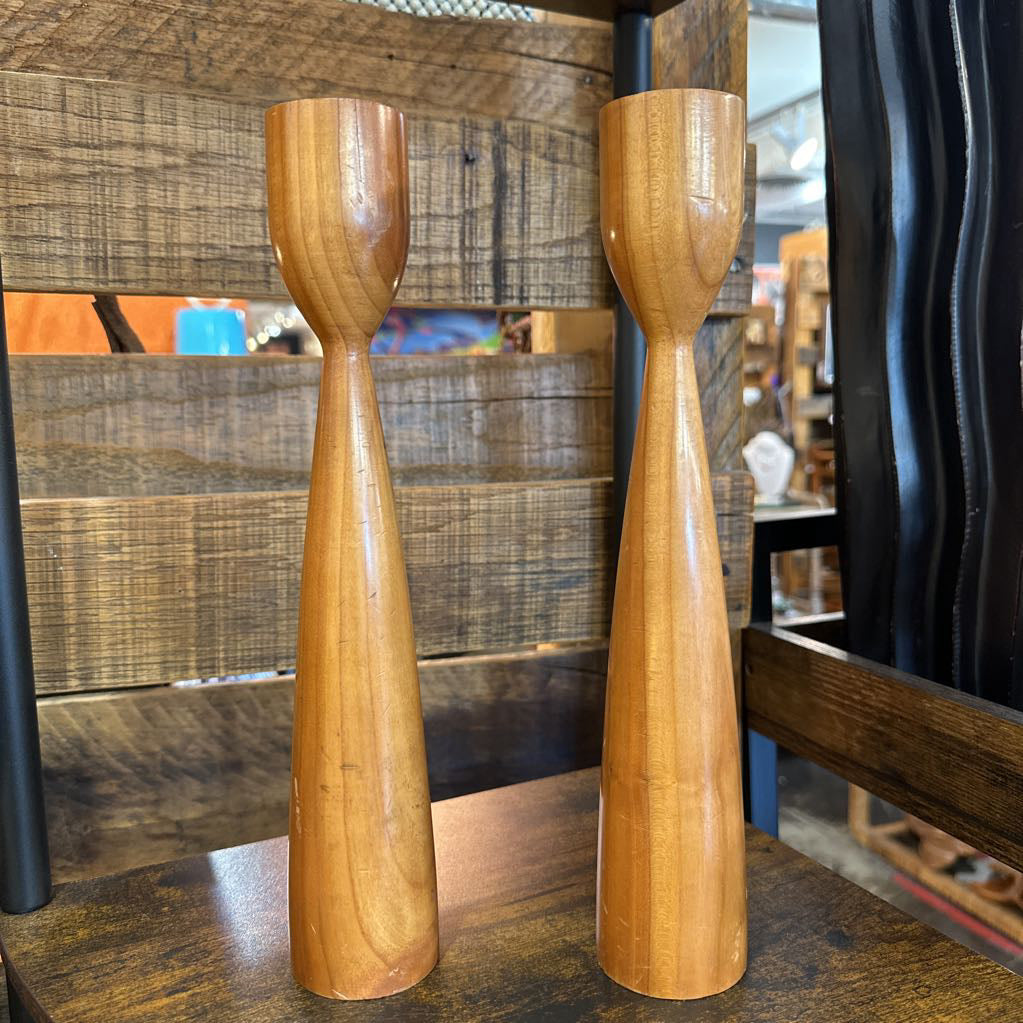 Two wooden candle holders on a wooden surface with a blurred background