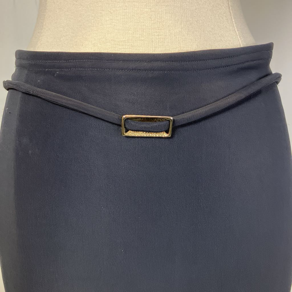 Black skirt with a gold buckle on a mannequin against a neutral background