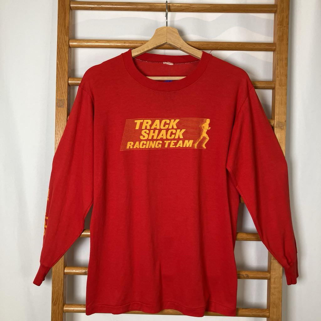 Red long-sleeve shirt with yellow text on a wooden rack