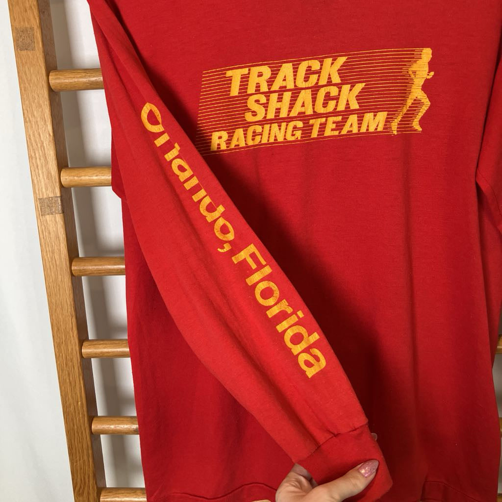 Red sweatshirt with yellow text and graphics on a wooden rack