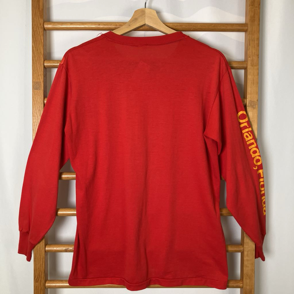 Red long-sleeve shirt with 'Orlando' text on a wooden rack