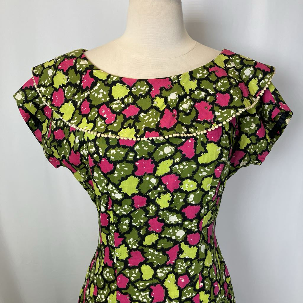 Mannequin wearing a dress with a green and pink floral pattern on a white background