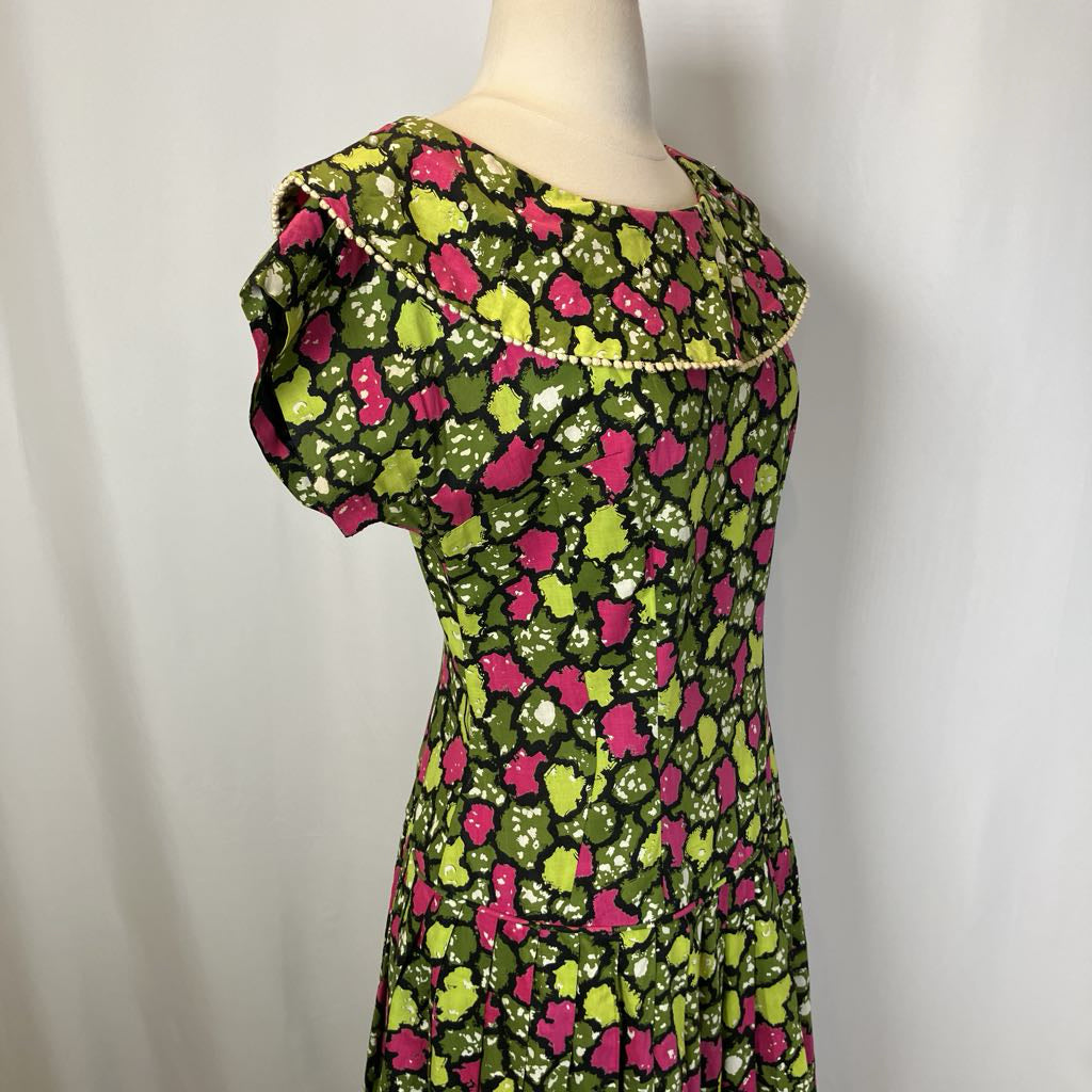 Mannequin wearing a floral dress with pink and green pattern on a plain background