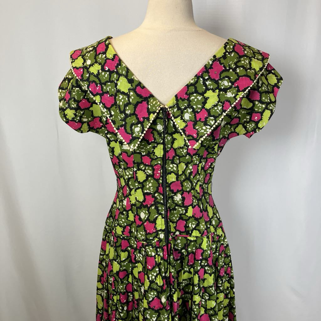 Green and pink floral dress on a mannequin against a white background