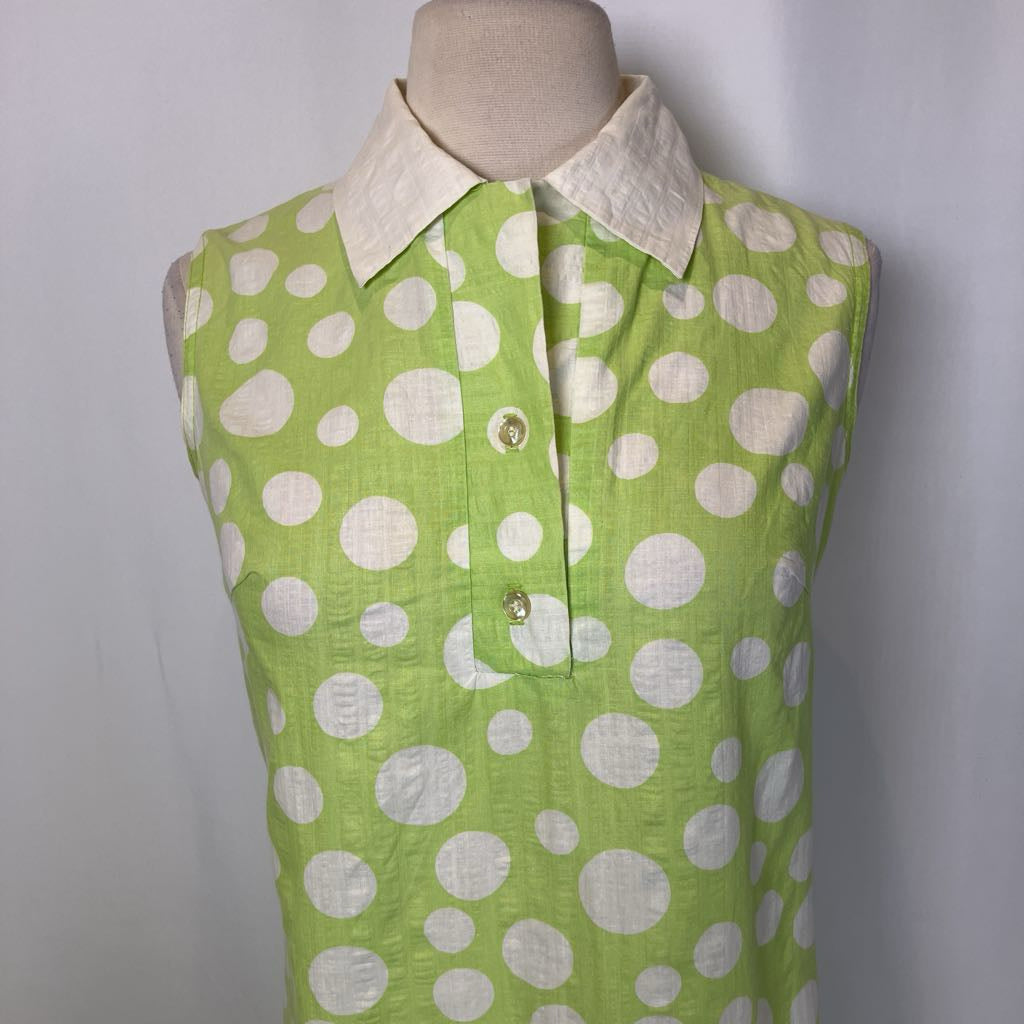 Green sleeveless shirt with white polka dots on a mannequin against a plain background