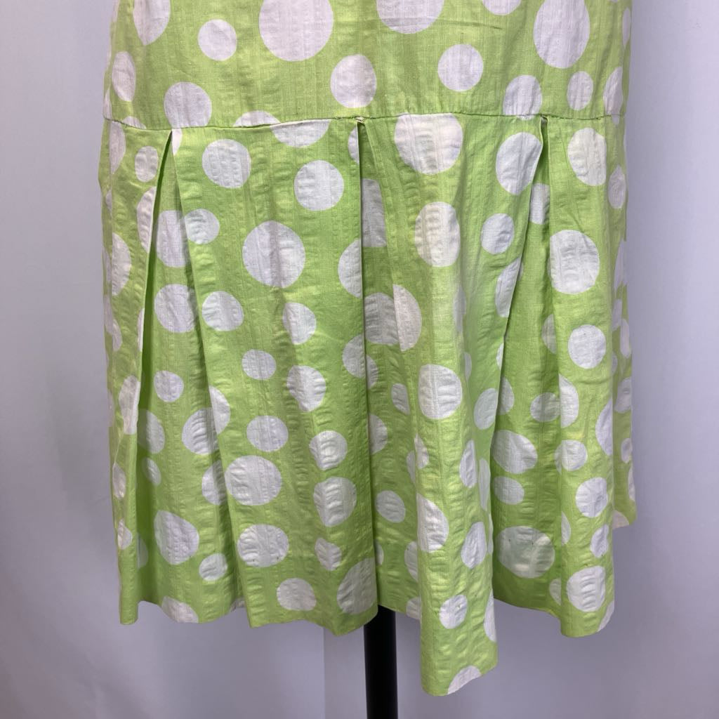 Green dress with white polka dots on a mannequin against a white background