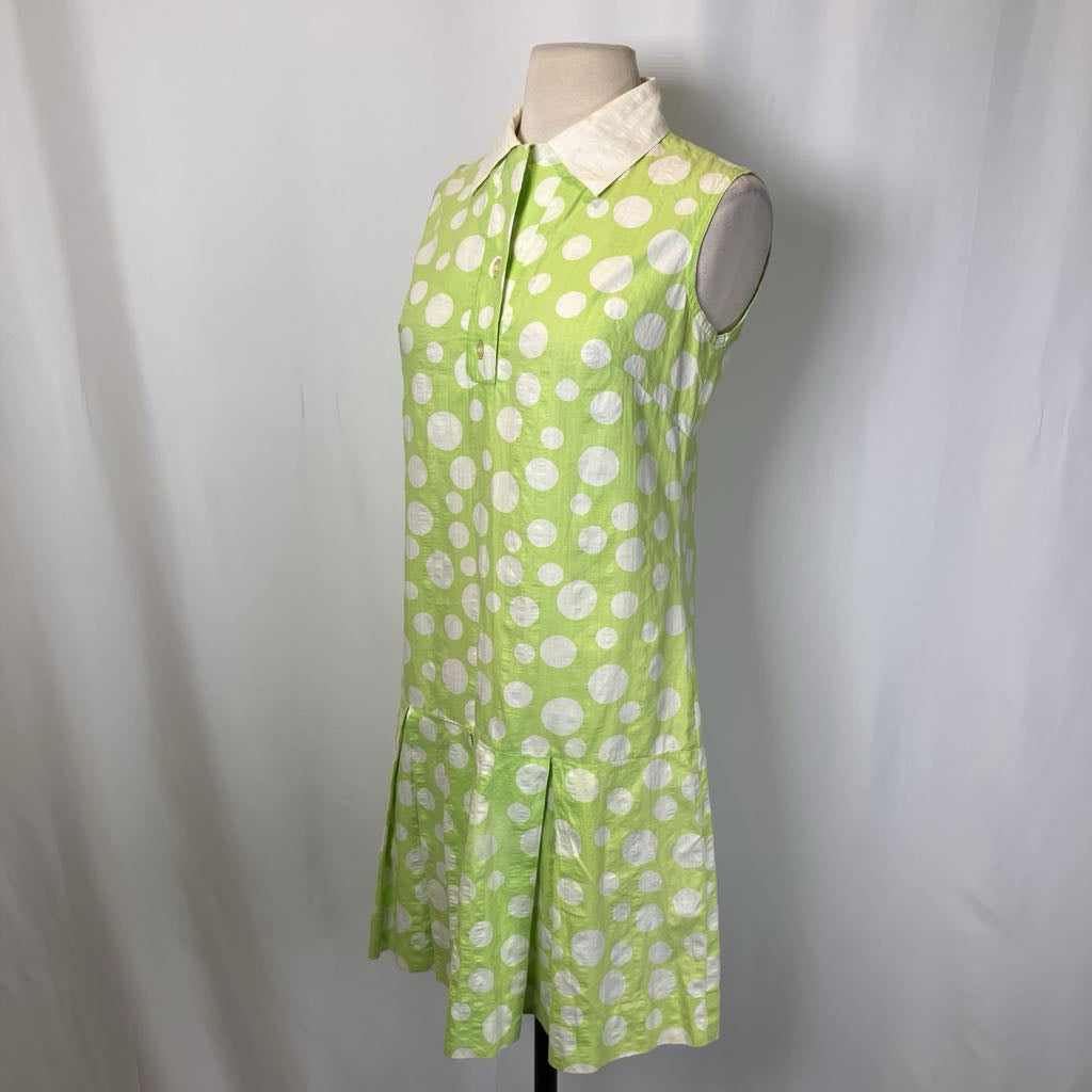 Green dress with white polka dots on a mannequin against a plain background